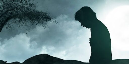 Silhouette of scary zombie with blood and wound on his body standing with a night scene background